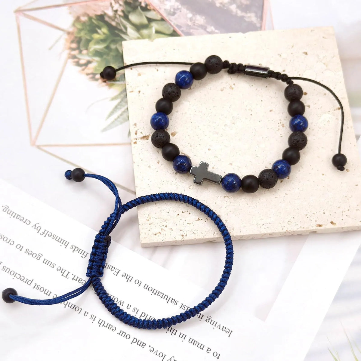 Hand-woven cross bracelet set with lapis lazuli and black matte volcanic stone beads in blue or black rope braid