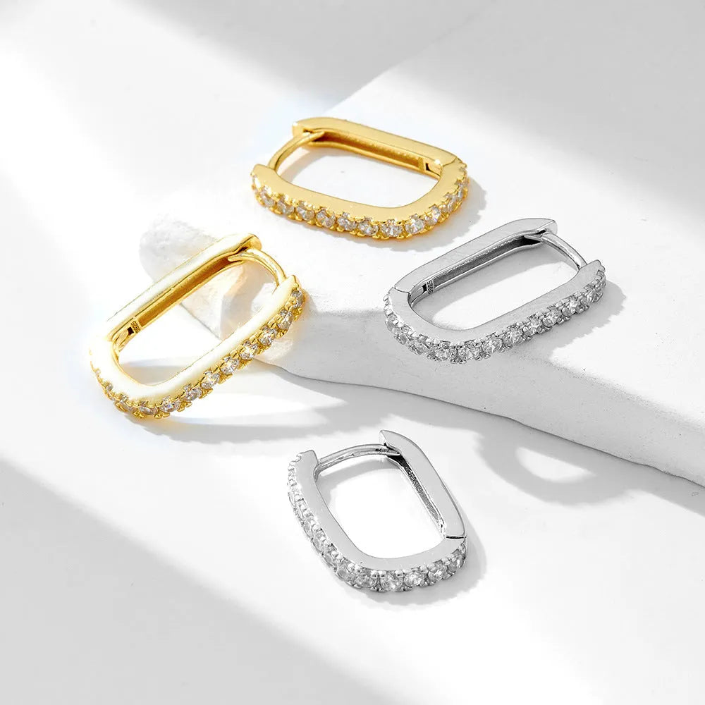 A pair of oval zircon clip earrings in sterling silver, shown in yellow and white finish options.