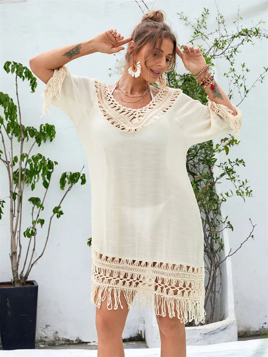 Apricot coloured long hand-crocheted beach dress on a hanger.