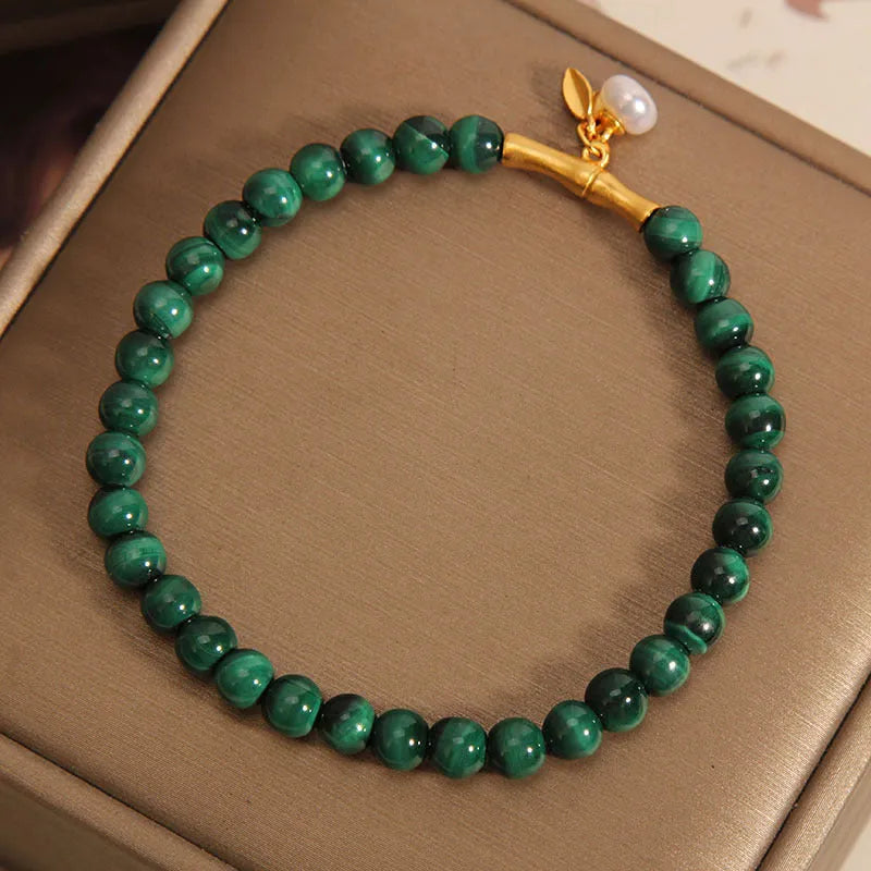 Close-up of a women's white crystal bracelet with a lucky bamboo charm on an elasticated band.