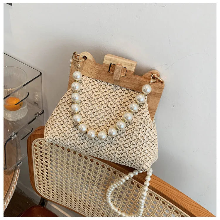 Beige straw woven women's shoulder bag with pearl chain strap showing front view