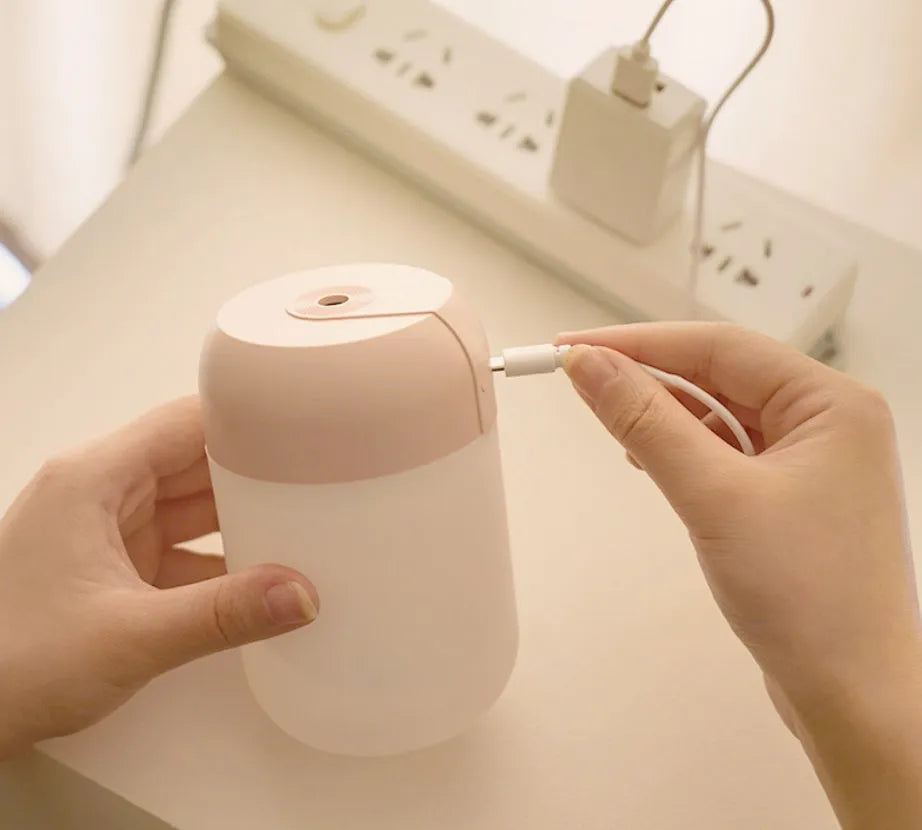 White cylindrical USB-powered mini humidifier with aromatherapy function on a wooden desk.