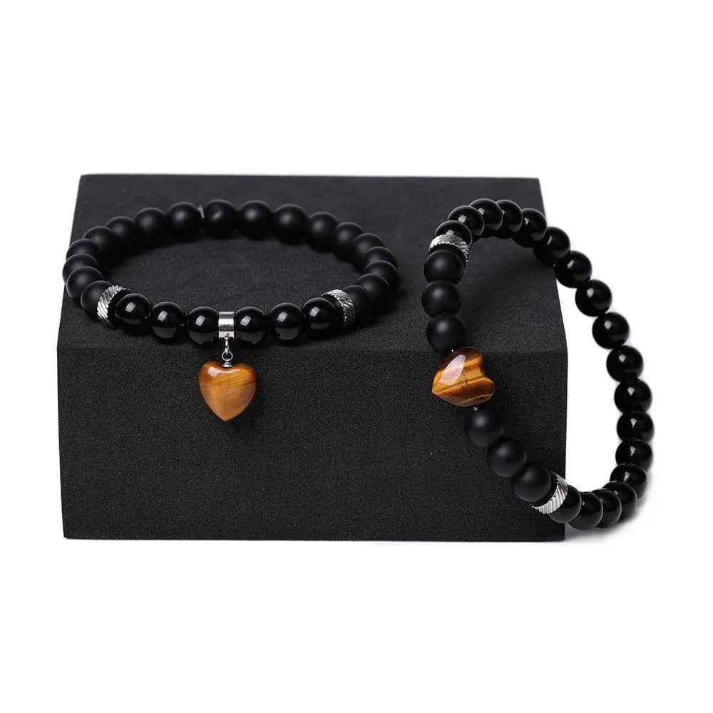 A pair of natural stone heart bracelets for couples on a background, showing geometric polished gemstone designs.