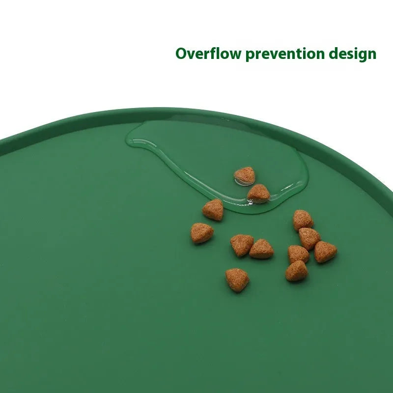 Green silicone cat feeding placemat with food and water bowls on top on a wooden floor.