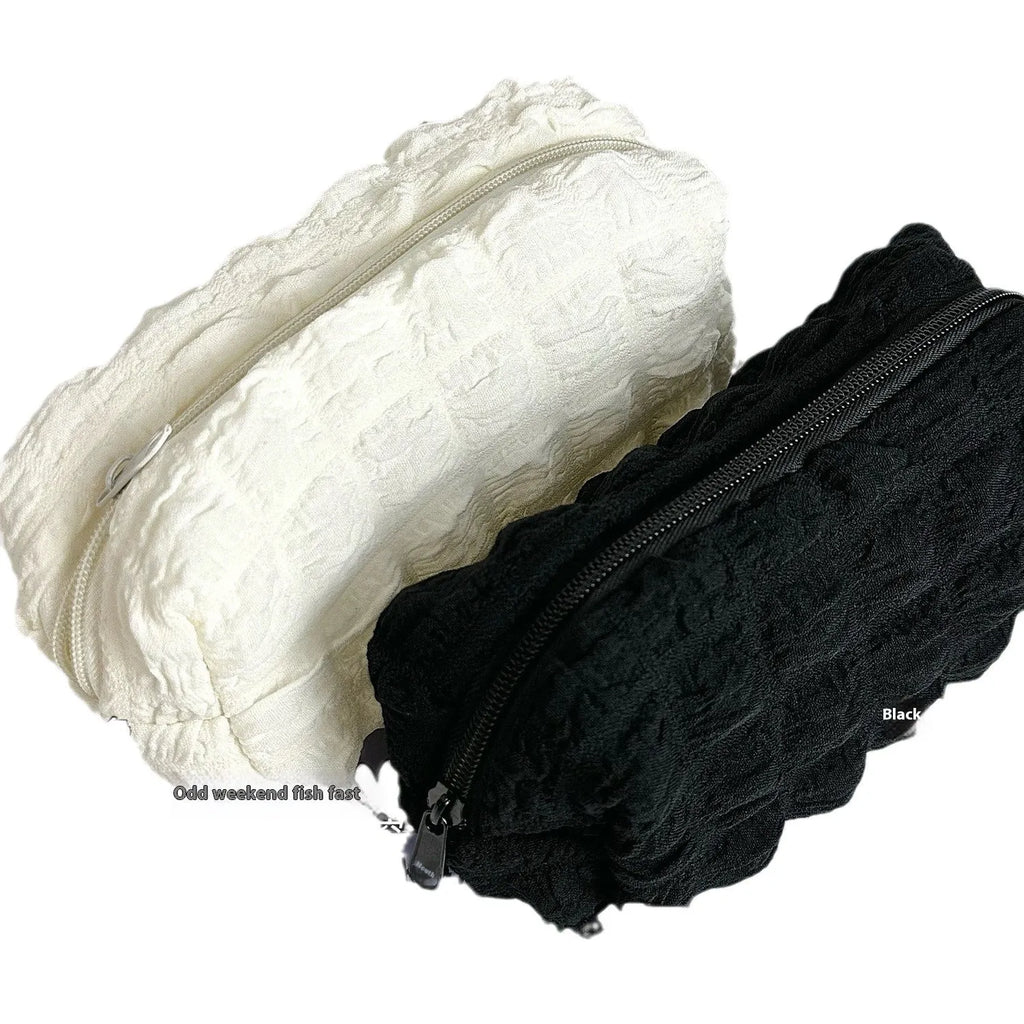 Beige and black soft fabric pencil case with a cream puff design and zip closure.