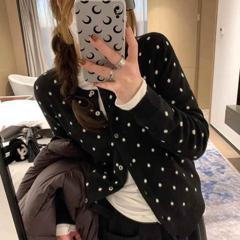 Women's loose-fit gray dot patterned knitted cardigan in black, showcasing crocheted flower detail.