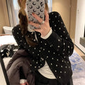 Women's loose-fit gray dot patterned knitted cardigan in black, showcasing crocheted flower detail.