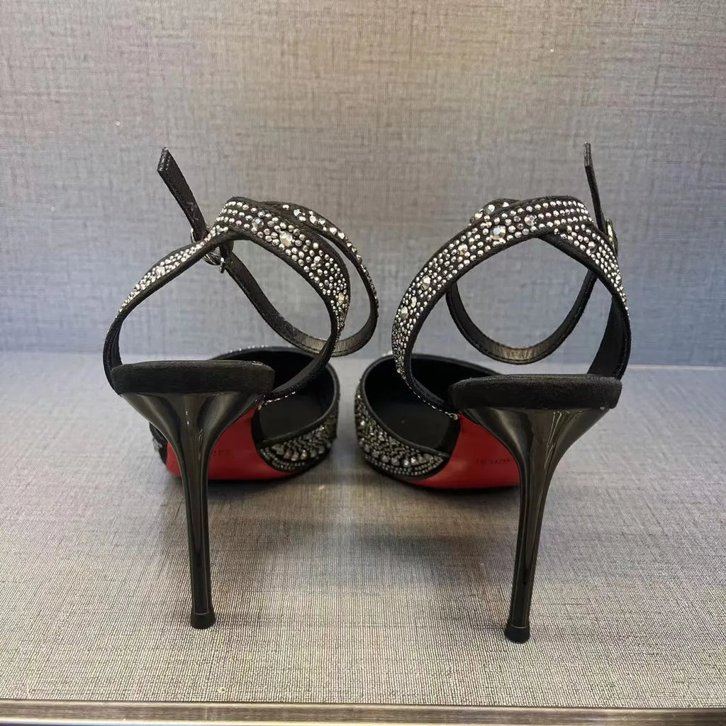 Women's black hollow high heels with red sole and stiletto heel on a plain background.