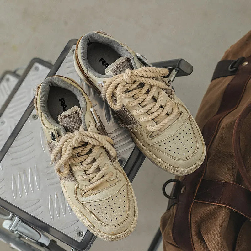 Beige low-top men's skateboard sneakers with a round toe and front lace-up on a rubber sole.