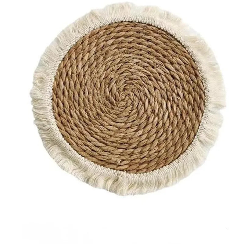 Round natural papyrus straw placemat with tassel detailing on a table.