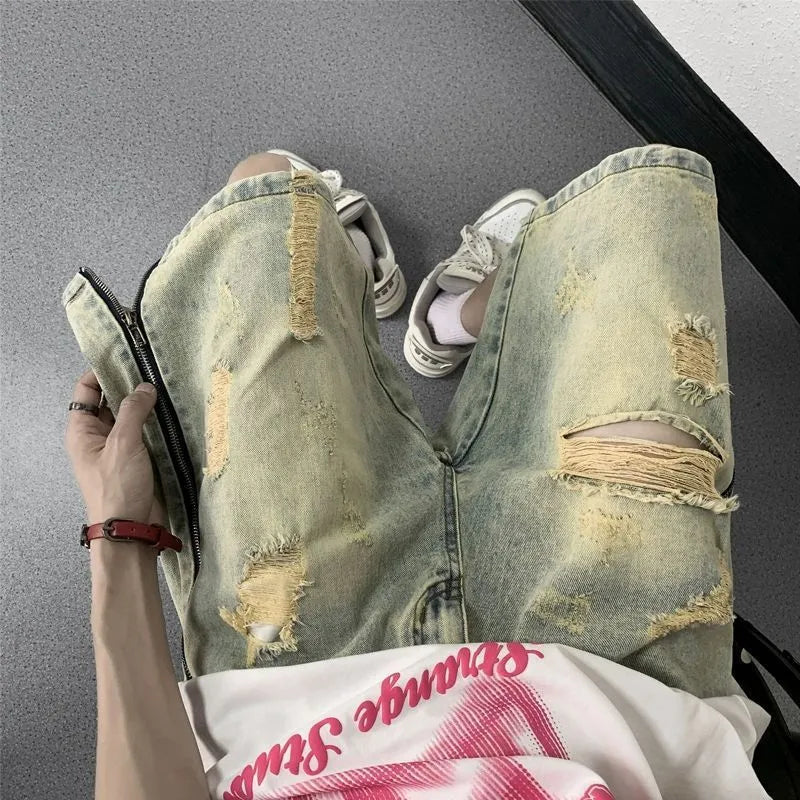 Blue men's loose fit denim shorts with distressed rip details and a yellow mud wash finish.