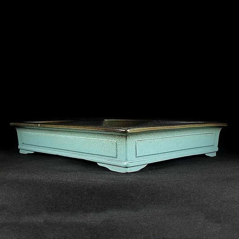 Handmade retro green ceramic bonsai flower pot with crackled glaze on a surface.