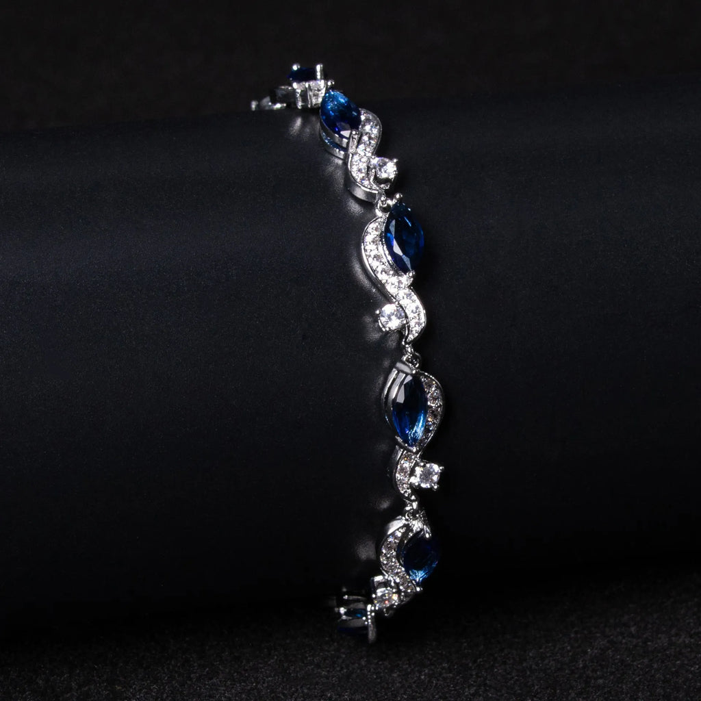 Women's copper geometric line bracelet with inlaid blue zircon stones on a white background