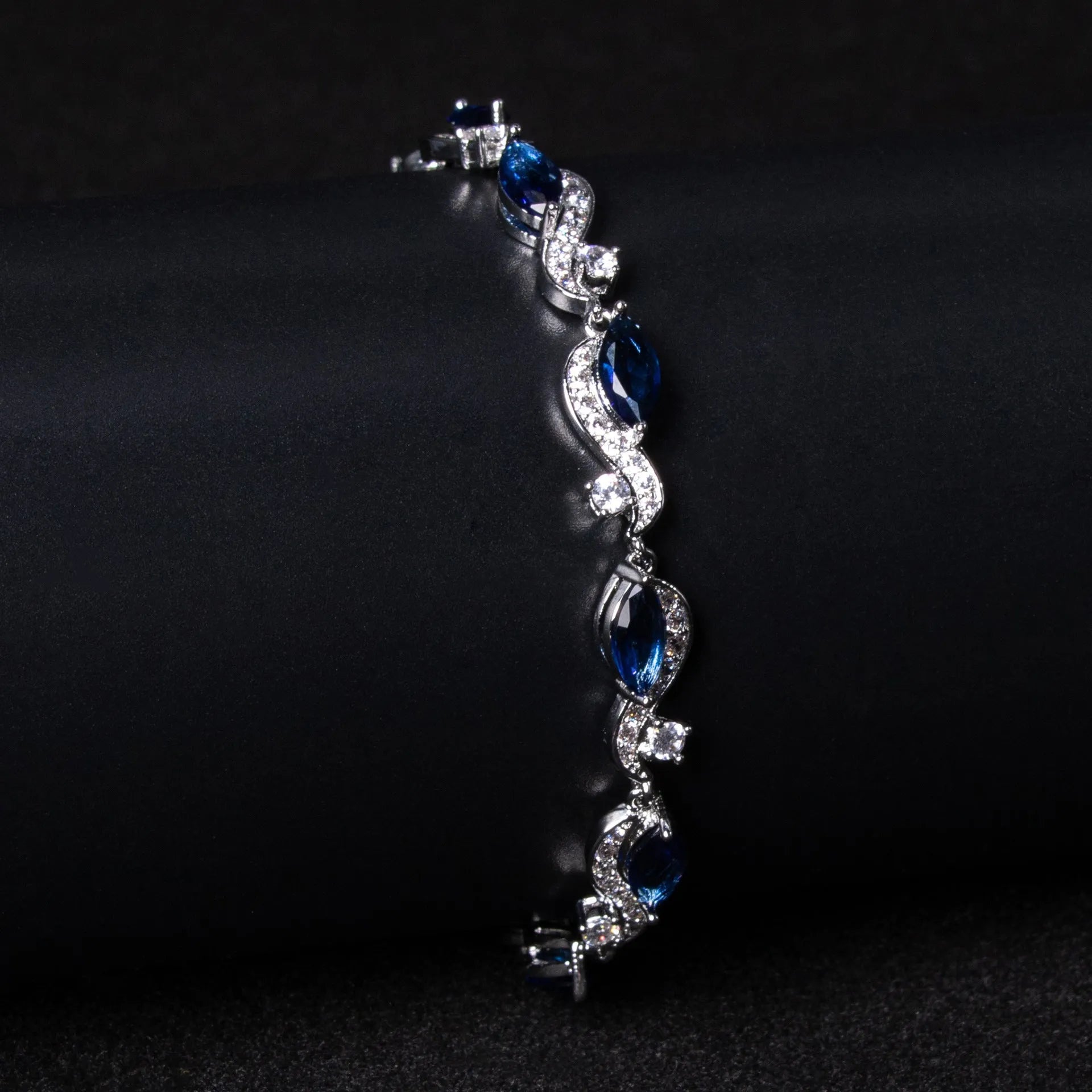 Women's copper geometric line bracelet with inlaid blue zircon stones on a white background