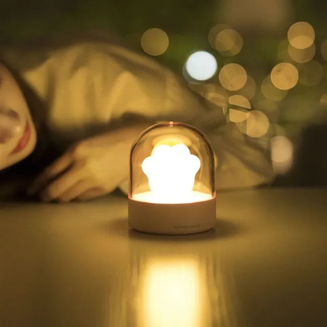 Grey and pink cat paw shaped night light with USB charging cable and musical rotation feature