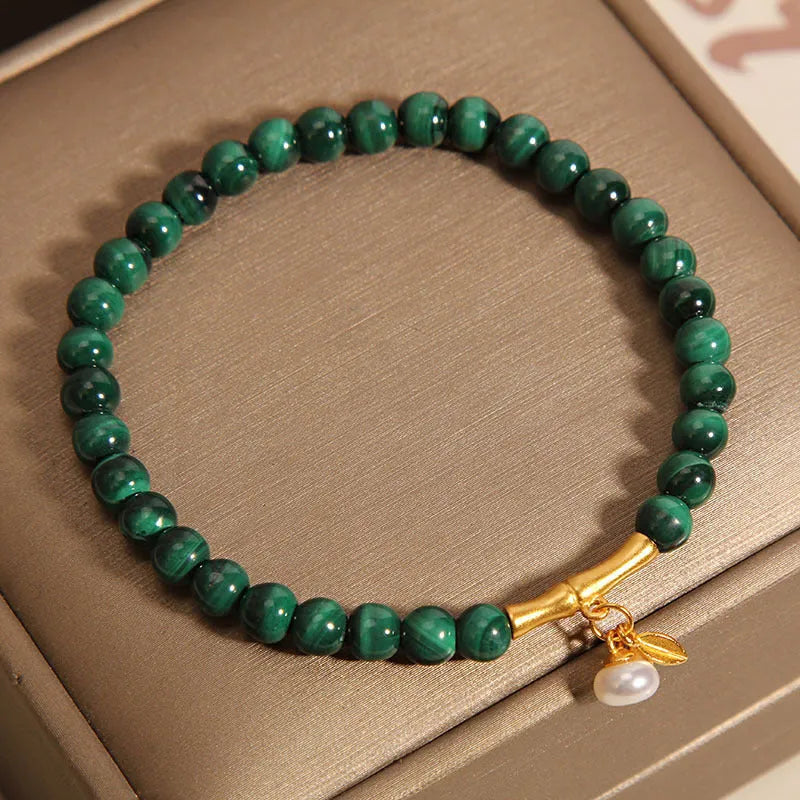 Close-up of a women's white crystal bracelet with a lucky bamboo charm on an elasticated band.