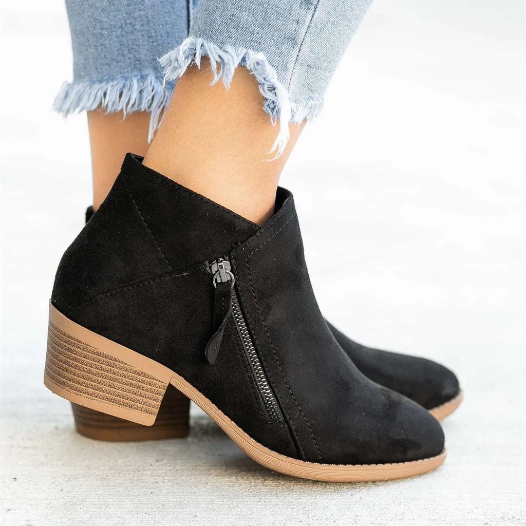 Women's blue suede Dr Martens ankle boots with a side zip and chunky heel on a white background.