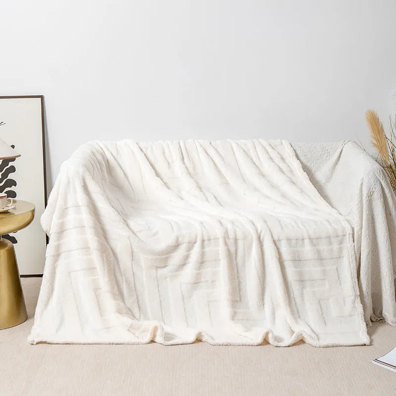 A square thick coral fleece blanket in a solid colour or floral pattern, shown draped over a sofa.