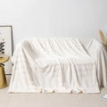 A square thick coral fleece blanket in a solid colour or floral pattern, shown draped over a sofa.