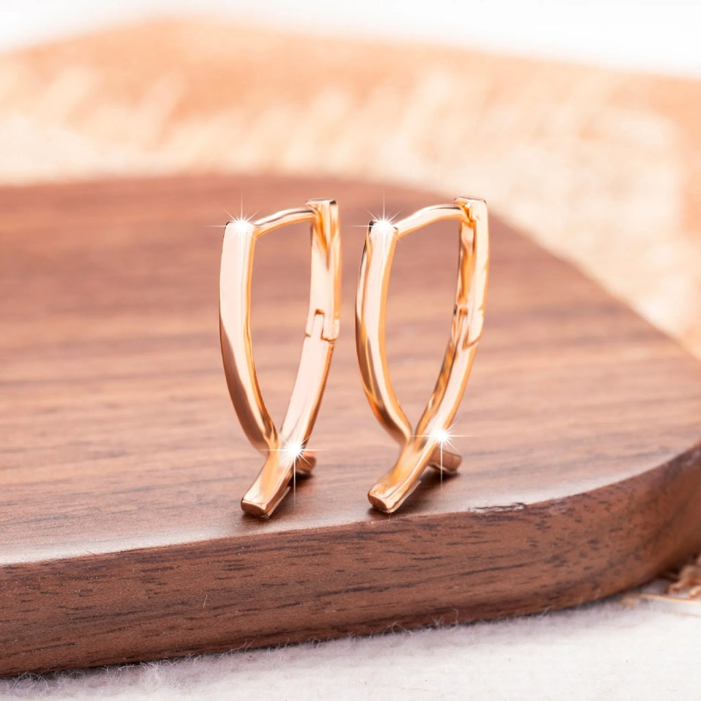 Rose gold coloured cross shaped drop earrings with contemporary light luxury styling