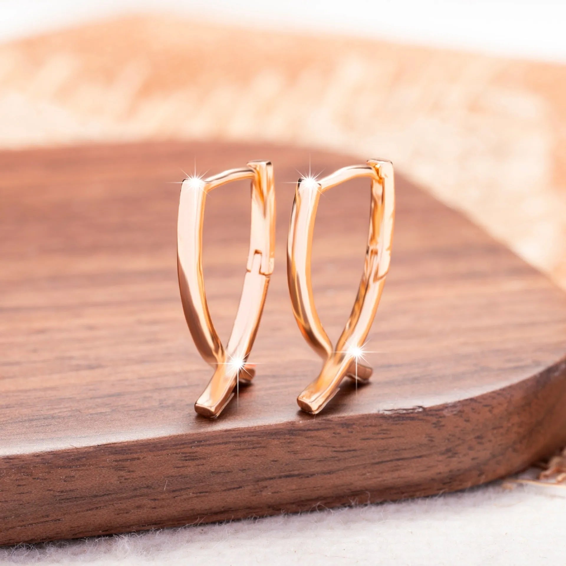 Rose gold coloured cross shaped drop earrings with contemporary light luxury styling