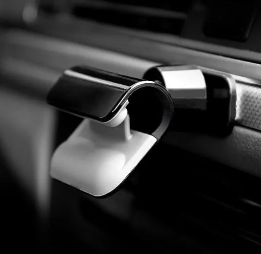Black gravity car phone holder mounted on a car air vent, showing 360-degree rotation and universal phone grip.