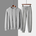 Men's light gray cashmere hoodie and matching trousers laid out as a complete casual two-piece set.
