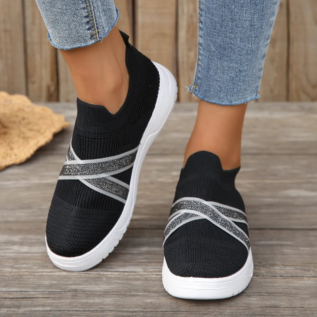 Black women's flat shoes with flyknit mesh upper, round toe, tassel detail, and rubber sole.
