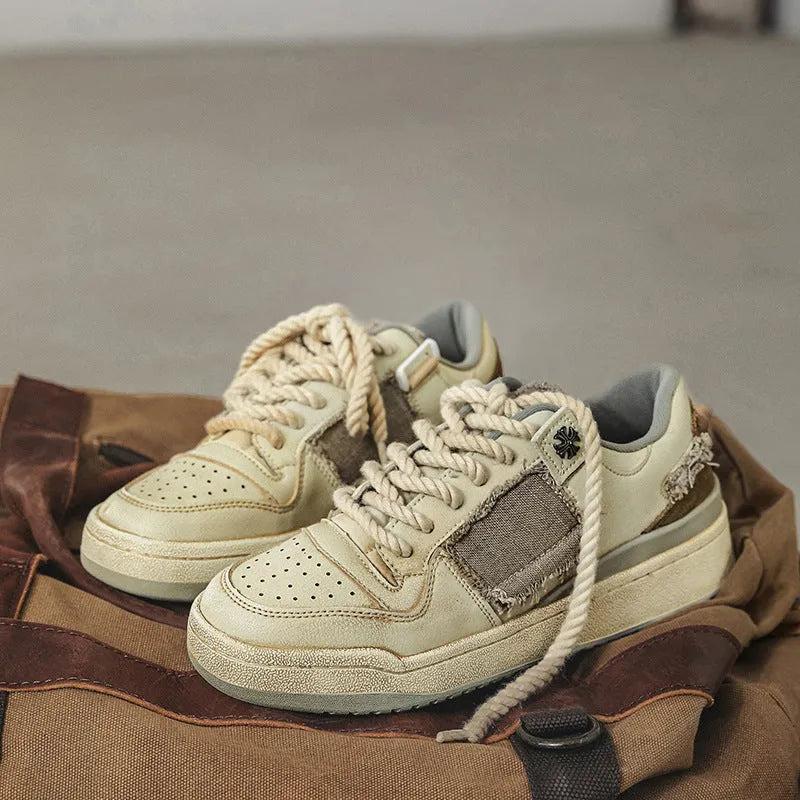 Beige low-top men's skateboard sneakers with a round toe and front lace-up on a rubber sole.