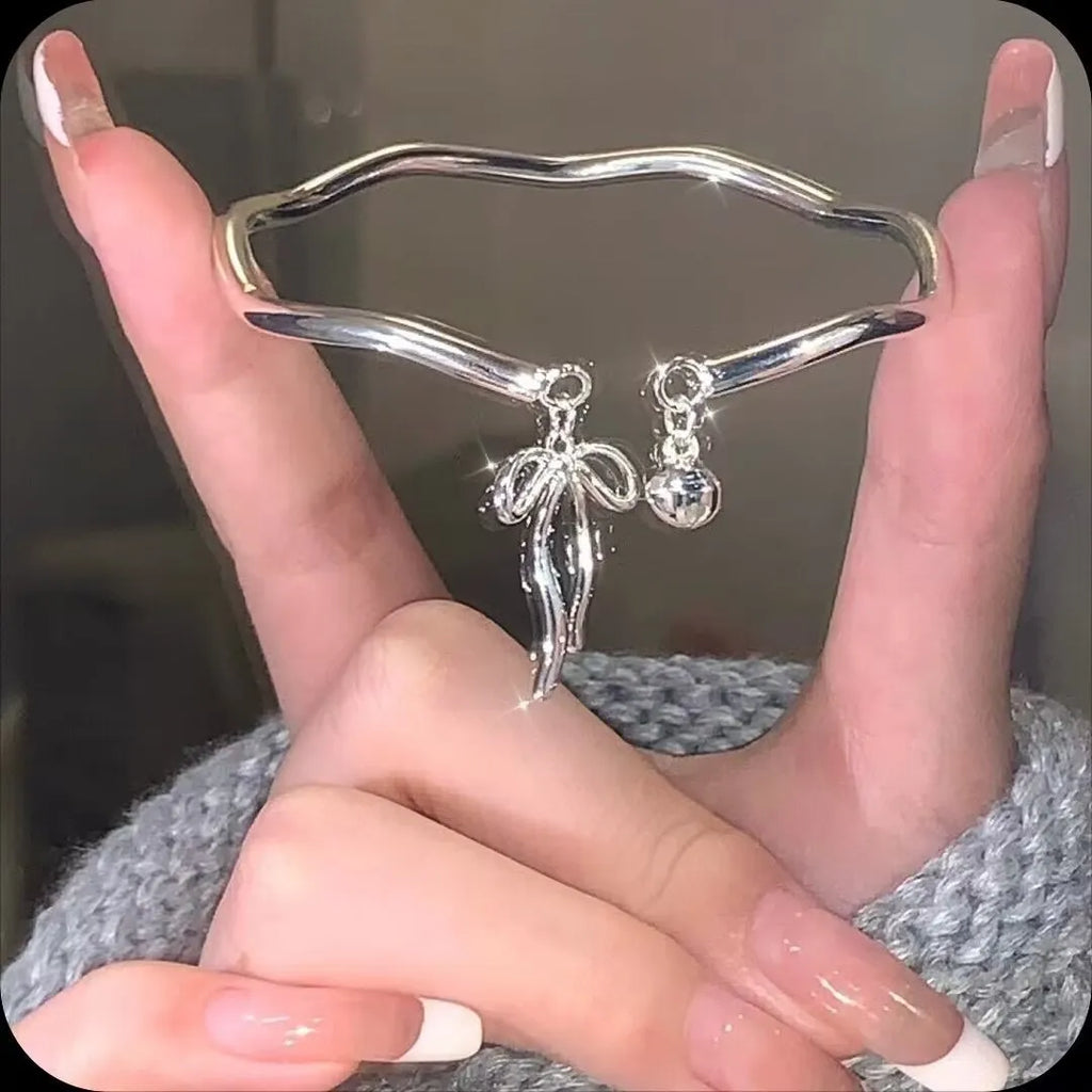 Silver adjustable bracelet with bow charm and opening bell clasp