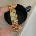 Women's antique-style bracelet watch with small white dial on a silver strap, showing butterfly buckle.