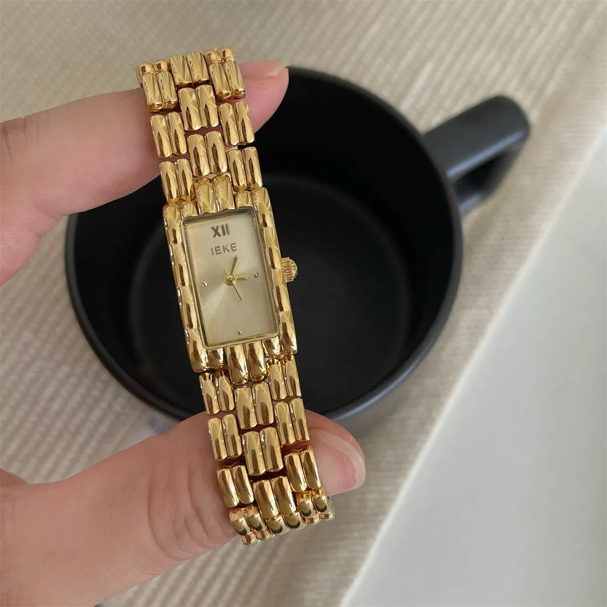 Women's antique-style bracelet watch with small white dial on a silver strap, showing butterfly buckle.