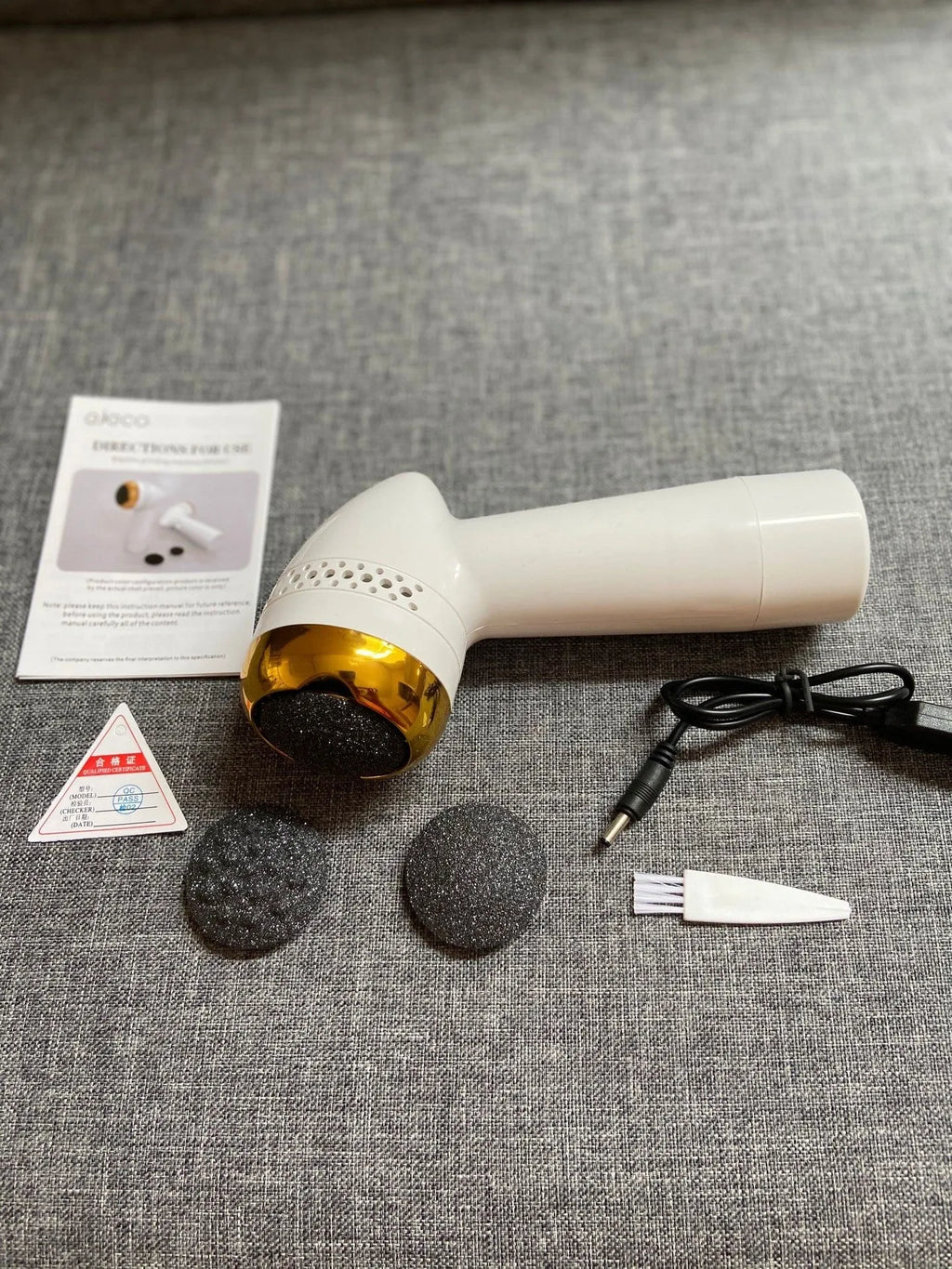 Electric vacuum foot grinder with quartz grinding head in a metallic finish, shown removing calluses on dry skin.