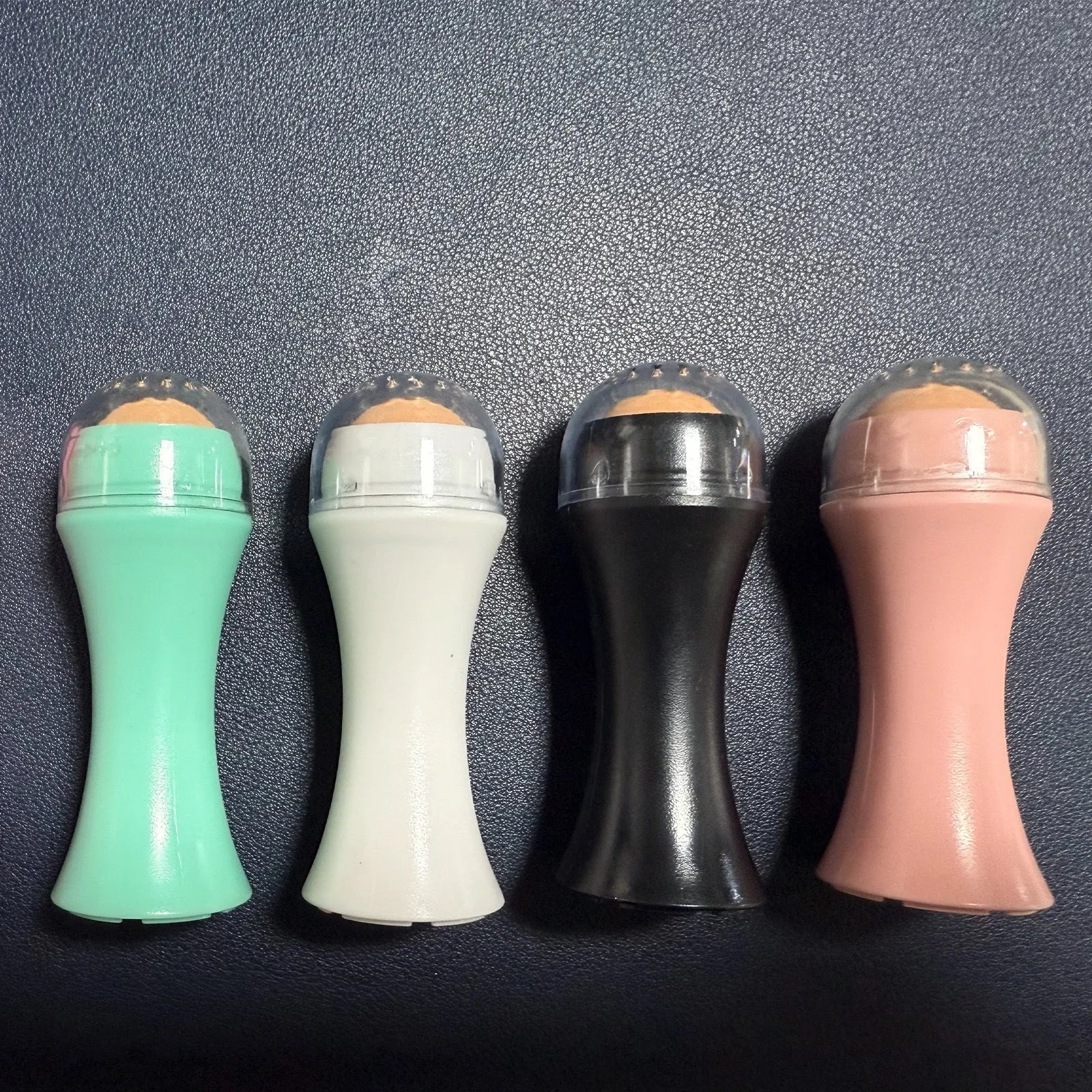 Volcanic stone portable facial roller for oily skin control in black, green, pink, or white.