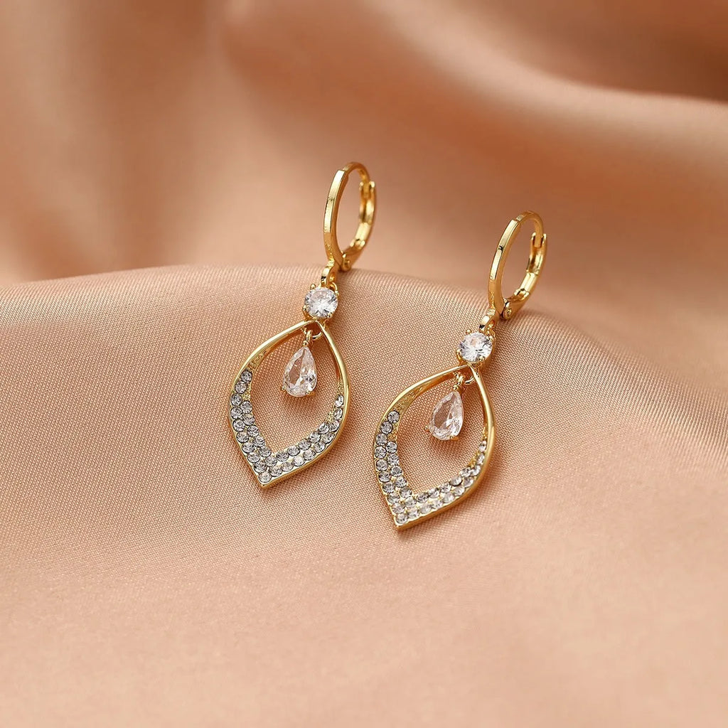 Close-up of a woman's gold-coloured water drop tassel earring with a teardrop shape and dangling details.