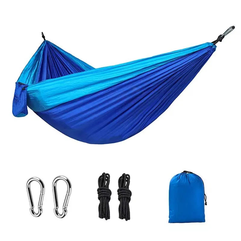 Blue nylon parachute cloth camping hammock hanging between two trees, showing its full 270cm length.