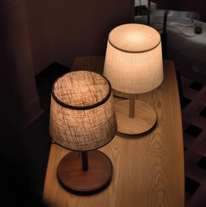Walnut coloured solid wood desk lamp with a white cloth lampshade and a black cable switch.