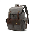 Retro-style canvas backpack in military green with antique bronze hardware, shown with a 16-inch laptop.