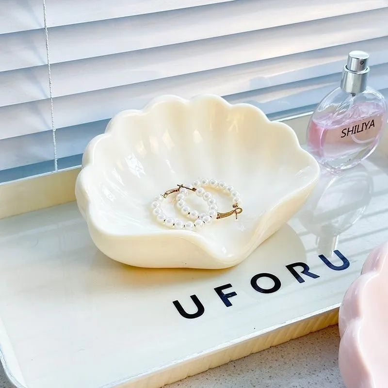 White shell-shaped plastic soap dish with drainage holes on a bathroom counter.