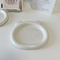 White porcelain plant saucer with a bear doodle design, shown next to a potted plant.