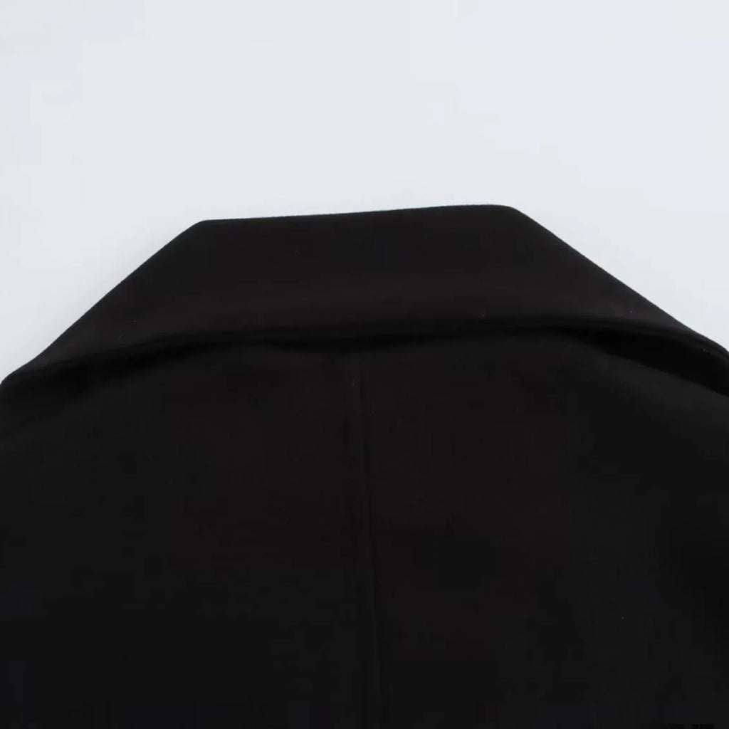 Women's long black coat with a grey artificial fur collar and front pockets.