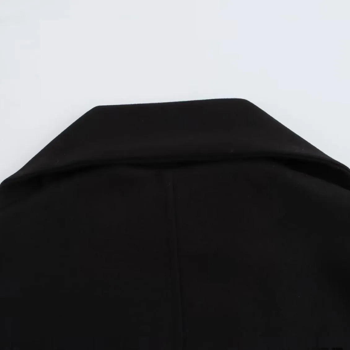 Women's long black coat with a grey artificial fur collar and front pockets.