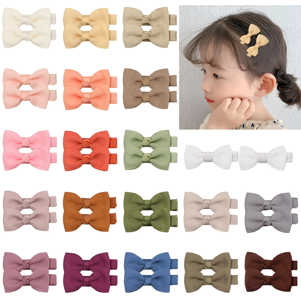 Assortment of pastel-coloured baby hair barrettes and bows laid out on a white background.