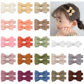Assortment of pastel-coloured baby hair barrettes and bows laid out on a white background.