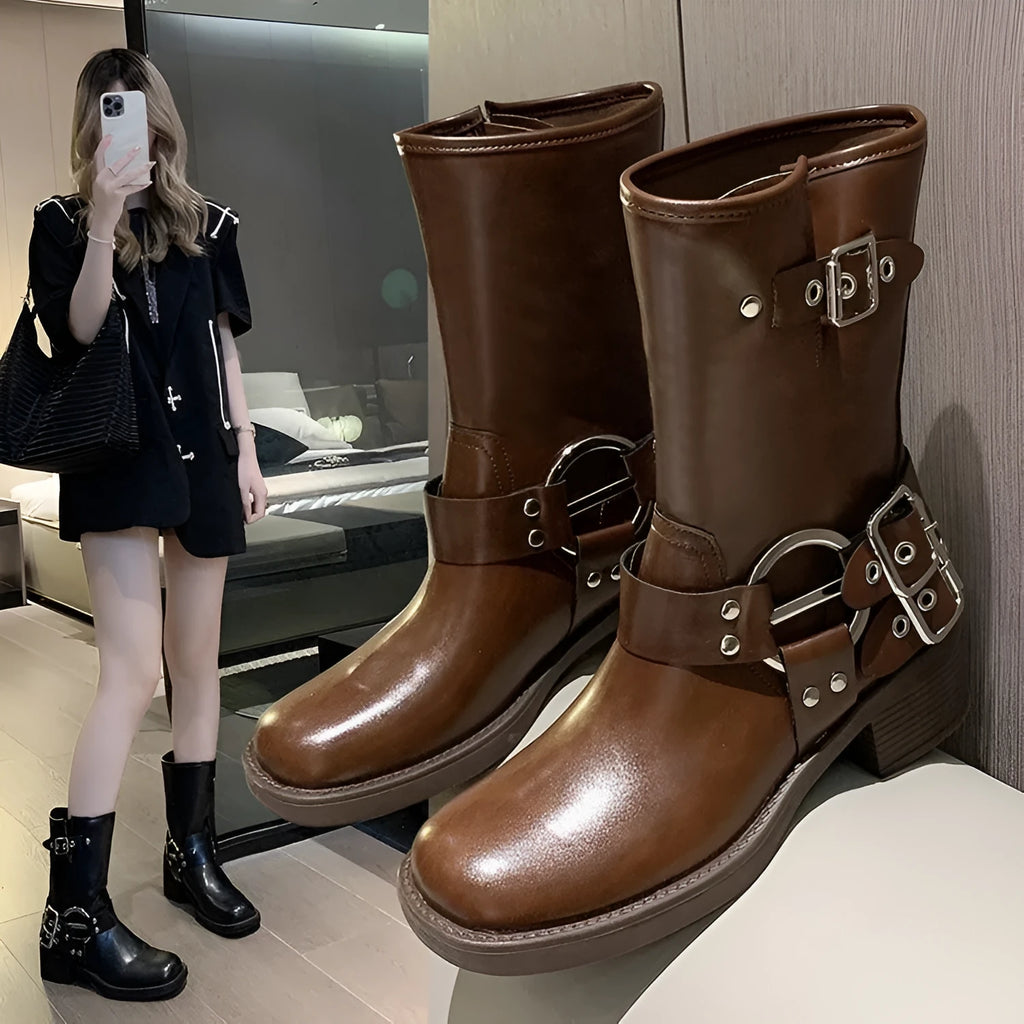 Women's black platform boots with buckle decoration at mid-calf height on a neutral background