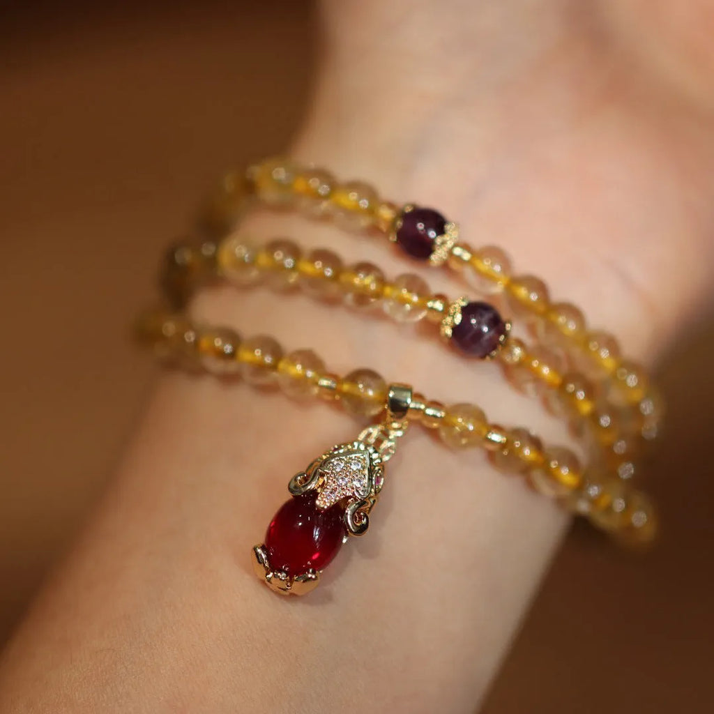 Natural Brazil gold rutilated quartz Chinese style bracelet with three gold rings and chopstick hanging detail.