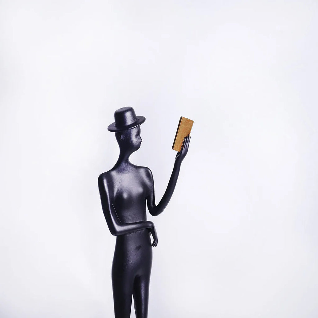 Black metal reading woman desktop sculpture made of cast aluminium measuring 51 cm tall