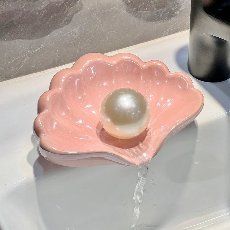 White shell-shaped plastic soap dish with drainage holes on a bathroom counter.