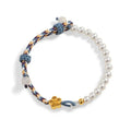 Peach-coloured adjustable cord bracelet with Chinese flower weaving and pearl details.