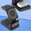 Black magnetic three-in-one wireless charger with clock on desk charging phone, watch, and earbuds
